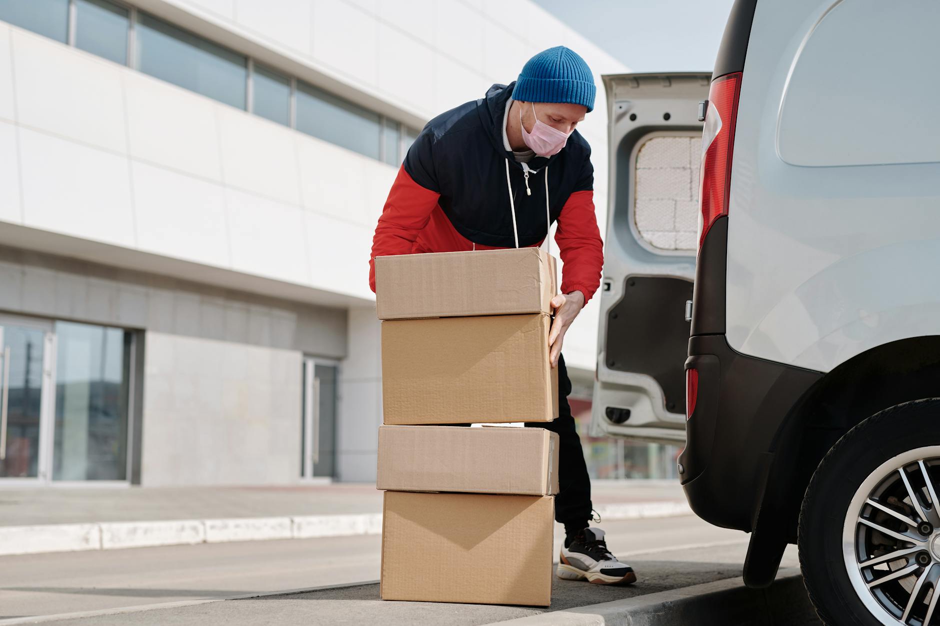 delivery man wearing a face mask carrying boxes